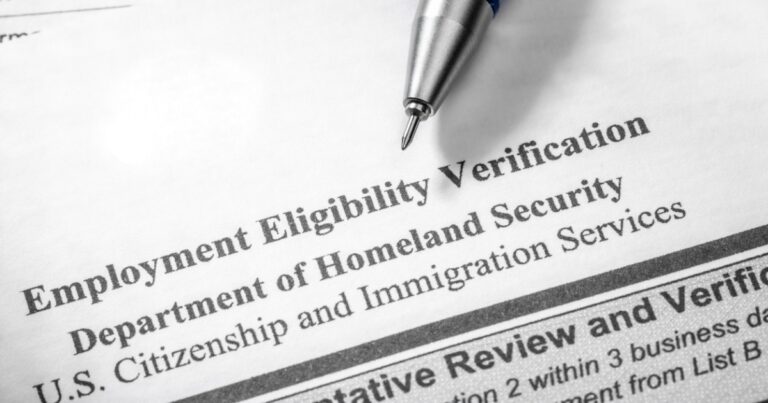 Part of the Form I-9 can be read. A pen tip is visible at top Employment Eligibility Verification Department of Homeland Security U.S. Citizenship and Immigration Services