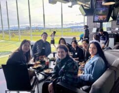 Group enjoying food at a table near a golf course.
