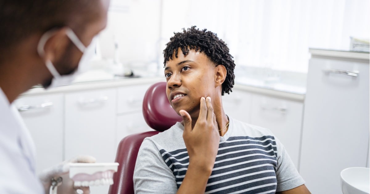 Teenager in dental chair showing dentist location of discomfort.